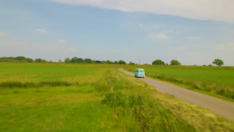 Approaching-VW-van-in-countryside-from-behind,-aerial-view