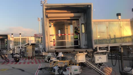 View-of-the-sky-bridge-retracting-from-an-airplane-at-Charles-De-Gaulle-Airport-ahead-of-take-off-with-the-gate-coming-down-and-worker-moving-downstairs