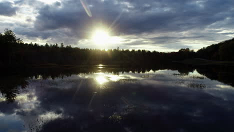 Langsam-Bewegte-Drohnenaufnahme-Eines-Sonnenuntergangs-über-Einem-Ruhigen,-Spiegelglatten-See