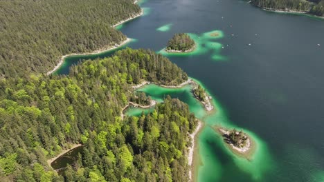 Vista-Aérea-De-La-Intrincada-Costa-De-Eibsee-Con-Aguas-Verde-Esmeralda-E-Islas-Densamente-Boscosas-En-Grainau,-Alemania