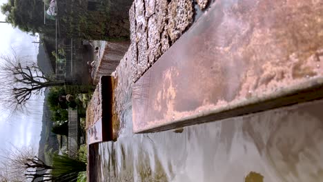 A-vertical-video-captures-the-cascading-thermal-pools-of-Poca-da-Dona-Beija,-tucked-away-in-Furnas,-Sao-Miguel,-amidst-the-stunning-landscapes-of-the-Azores-in-Portugal