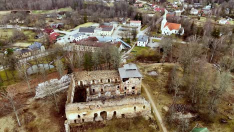 Luftbild-Panorama,-Das-Die-Burgruine-Ruana-Dreht,-Lettisches-Herbstdorf