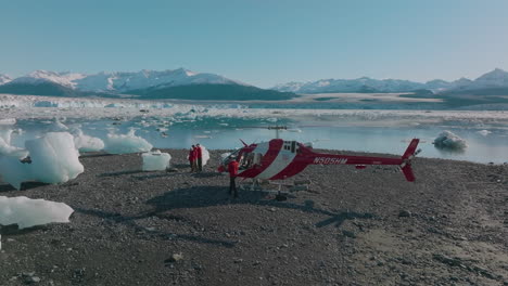 Vista-Aérea-De-Un-Helicóptero-Y-Turistas-Volando-Drones-En-El-Paisaje-ártico-Helado