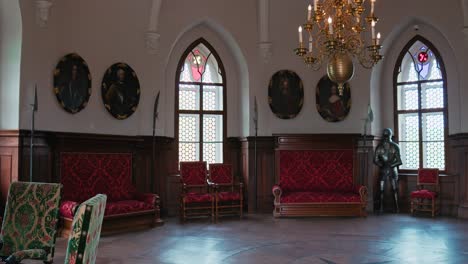 Opulent-Chivalric-hall-in-Trakoscan-Castle-with-red-upholstered-furniture,-armor-display,-and-historical-portraits