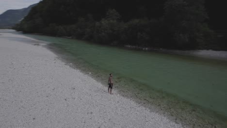 Vídeo-De-Un-Dron-De-360º-Sobre-Una-Persona-Tatuada-En-El-Lago-Isonzo-Con-Montañas-En-El-Horizonte