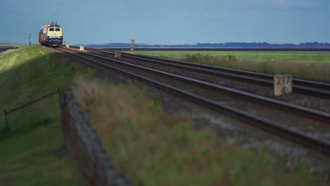 Una-Toma-Ajustada-De-Un-Tren-De-Carga-Acercándose-Desde-La-Distancia-Y-Pasando