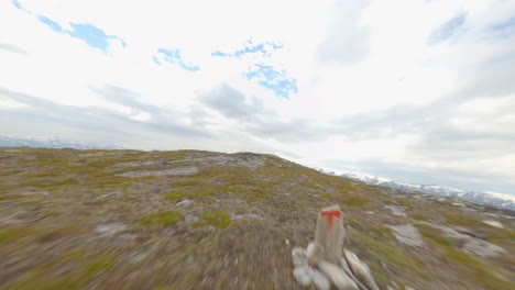 Sobrevuelo-Aéreo-En-La-Cima-De-La-Montaña-De-Rossnos-Y-Un-Hombre-De-Pie-En-El-Borde-De-La-Pared-Del-Acantilado,-Noruega