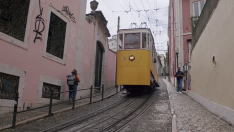 Vintage-yellow-trams-of-Lisbon-driving-up-the-slope-in-Lisbon-city,-Portugal