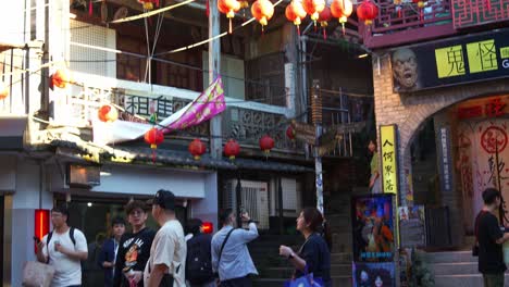 Toma-Inclinada-De-La-Bulliciosa-Plaza-De-La-Antigua-Calle-Jiufen,-Con-El-Museo-De-Historia-De-Los-Fantasmas-Y-Faroles-Rojos-Colgando-Sobre-La-Plaza,-Un-Popular-Lugar-Turístico-Ubicado-En-La-Ciudad-Montañosa-De-Taiwán.