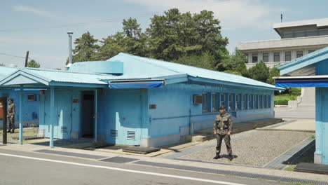 Aldea-De-Tregua-En-El-área-De-Seguridad-Conjunta-De-La-Zona-Desmilitarizada-De-Corea-Con-Un-Soldado-Surcoreano-Haciendo-Guardia,-Amplia-Panorámica-Hacia-La-Derecha-En-Cámara-Lenta