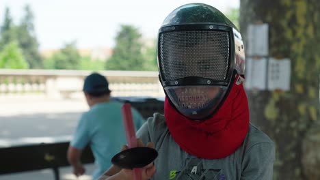 Slow-motion-shot-of-a-young-boy-putting-on-a-fencing-helmet-for-protection