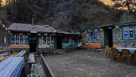 Tibetan-mountain-hut-in-Langtang-Valley,-featuring-seating-and-prayer-flags,-ideal-for-hikers-seeking-rest-amidst-serene-mountains