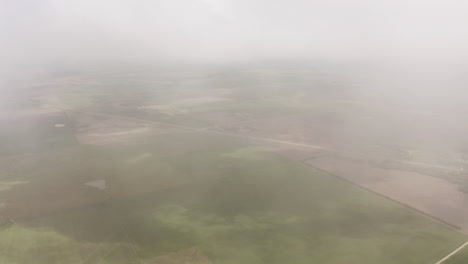 Eine-Drohne-Bewegt-Sich-Durch-Die-Wolken-über-Grasland-Und-Ackerland-Im-Mittleren-Westen-Der-USA