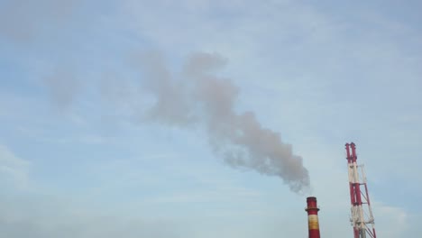 The-Chimney-Of-An-Industrial-Factory-In-Legnica,-Poland-With-Smoke-Rising-To-The-Air---Tilt-Up-Shot