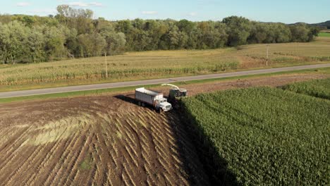 4K-aerial-view-of-a-harvester-starting-a-new-row-of-corn-chopping-into-a-truck-coming-towards-the-camera