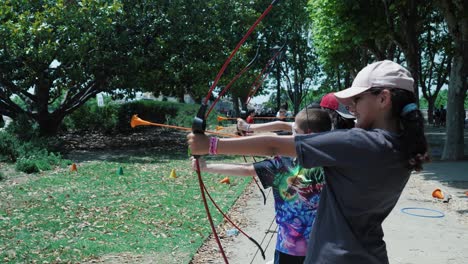 Slow-motion-shot-of-kids-lined-up-firing-plastic-arrows-at-a-target