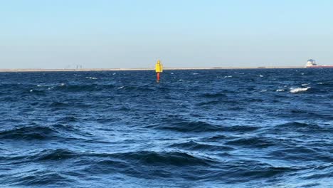 Yellow-buoy-bobbing-on-rough-sea-waves-under-clear-blue-sky