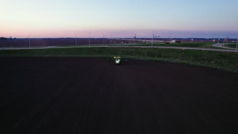 Sonnenuntergangsluftaufnahme-Eines-Traktors,-Der-In-Der-Abenddämmerung-Ein-Feld-Pflügt