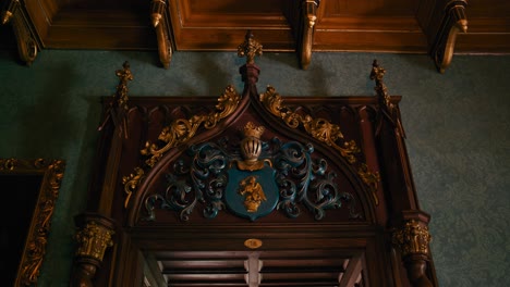 Ornate-wooden-doorway-with-intricate-carvings-and-a-crest-in-Trakošćan-Castle-,-Croatia