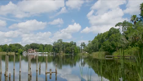 Timelapse-of-calm-Florida-lake-and-vegetation-with-clouds-rolling-by-with-blue-sky