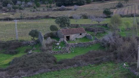 Vuelo-Orbital-Donde-Vemos-El-Deterioro-De-Una-Antigua-Casa-De-Piedra-Con-Sus-Muros-Caídos-Y-Otra-Posible-Habitación-Anexa-Casi-En-Ruinas