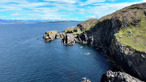 Drone-Volando-A-Lo-Largo-De-La-Costa-Rocosa-Mares-Azules-Tranquilos-Día-De-Verano,-Los-Bacalaos-Se-Dirigen-Al-Oeste-De-Cork,-Irlanda,-Camino-Atlántico-Salvaje