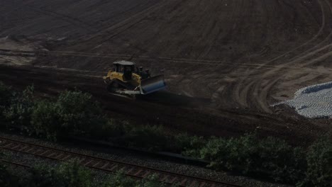 Bulldozer-moving-earth-creating-foundation-road-aerial-view-overlooking-early-morning-sunrise-construction-site