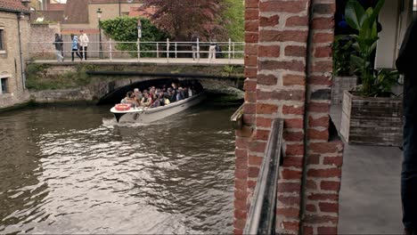 Tourist-Boat-Passing-Under-The-Bridge-On-Dijver-Canal-In-Bruges,-Belgium