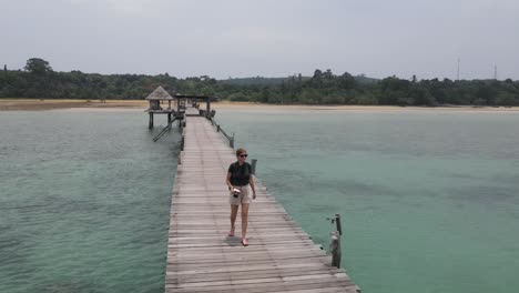 Female-Traveller-Walking-Along-Cinnamon-Boardwalk-At-Koh-Mak,-Thailand