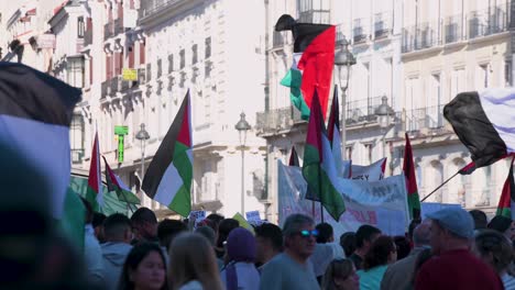Palästinensische-Flaggen-Wehen,-Während-Sich-Demonstranten-Während-Einer-Pro-palästinensischen-Demonstration-An-Der-Puerta-Del-Sol-In-Madrid,-Spanien,-Versammeln.