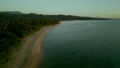 Golden-hour-aerial-of-idyllic-beach-coastline-and-forest,-Philippines