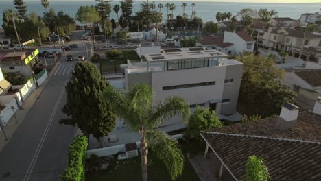 Aerial-view-of-a-luxury-house-overlooking-Sandy-Beach-in-Rincon,-Puerto-Rico-on-a-beautiful-day,-with-palm-trees-and-the-sea-in-the-background