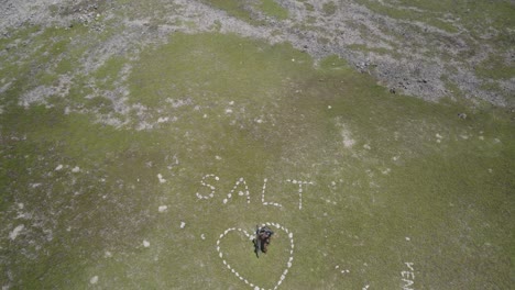 A-kiter-with-a-board-celebrating-inside-a-heart-shaped-salt-formation,-aerial-view