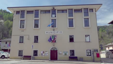 The-city-hall-of-Caldonazzo,-Trentino,-Italy-with-waving-flags-on-a-nice-and-sunny-day-in-April