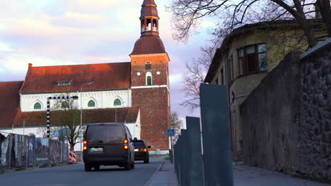 View-of-Saint-Simon-Church-from-Raina-street-in-Valmiera,-Latvia-with-traffic-on-road