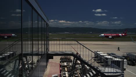 Avión-De-Air-Asia-En-La-Pista-Reflejándose-En-El-Cristal-De-La-Terminal