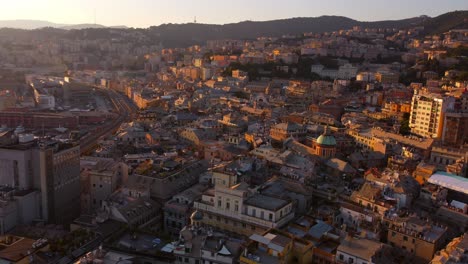 Genoa's-historical-center-at-sunset,-showcasing-the-dense-urban-landscape-and-warm-lighting,-aerial-view