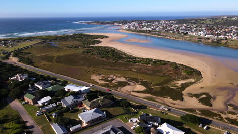 Antena-Sobre-Stilbaai-Este-Con-Vista-Panorámica-Sobre-La-Desembocadura-Del-Estuario-De-Goukou-Y-El-Lado-Oeste-De-La-Popular-Ciudad-Costera-En-Western-Cape,-Sudáfrica