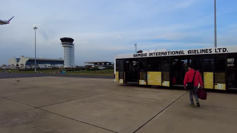 Passagiere-Steigen-Am-Terminal-Des-Internationalen-Flughafens-Banjul-Aus-Dem-Flugzeug-Der-SN-Brussels-Aus-Und-Besteigen-Den-GIA-Flughafenbus