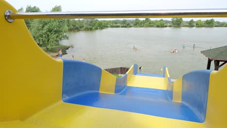 Looking-down-water-slide-to-people-swimming-in-city-park-lake