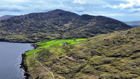 Drone-flying-to-farmstead-sheltered-in-the-mountains-of-West-Cork-in-Ireland,beautiful-remote-landscape