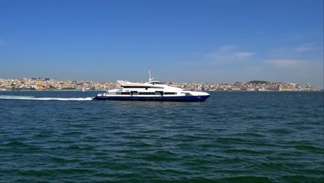 Scheduled-ferry-is-on-its-way-to-Cacilhas-on-the-Tagus-River,-with-a-stunning-view-of-Lisbon's-city-centre-in-the-background-on-a-sunny-day-in-Portugal