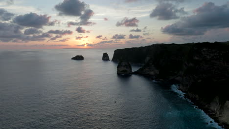 Puesta-De-Sol-Sobre-La-Costa-Del-Acantilado-Oscuro,-Nusa-Penida,-Indonesia,-Antena