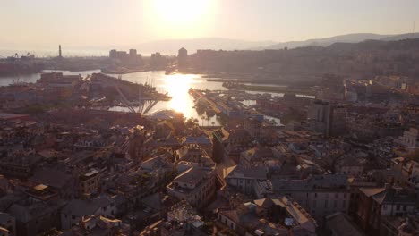 Genoa's-historic-center-at-sunset-with-sun-reflections-on-the-water,-aerial-view