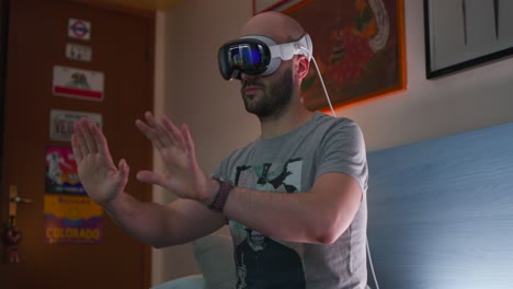 Male-engages-with-a-virtual-world-using-a-Apple-Vision-Pro-headset-Using-Hand-Gestures-Inside-Bedroom