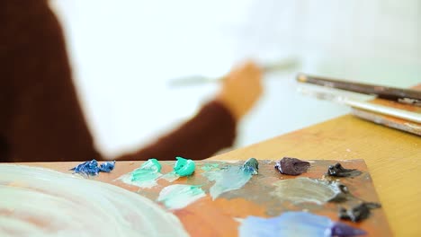 an-artist-painting-with-her-palette-in-the-foreground