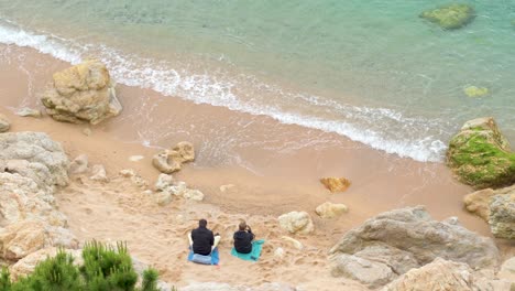 Top-view-of-a-couple-enjoying-the-beach-and-sea,-taking-some-photos-and-relaxing