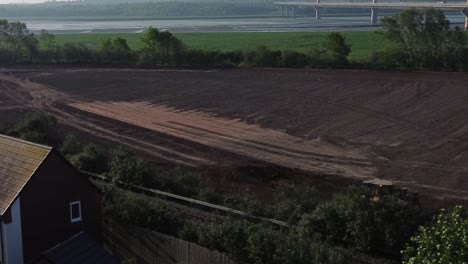 Vista-Aérea-Dando-Vueltas-A-La-Excavadora-Empujando-Tierra-Detrás-Del-Sitio-De-Construcción-De-Viviendas-En-El-Amanecer-Temprano-En-La-Mañana