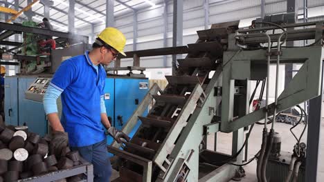 Side-angle-view-showing-men-pouring-raw-material-into-conveyor-line-and-moving-into-forging-plant,-Industrial-safety-first-concept