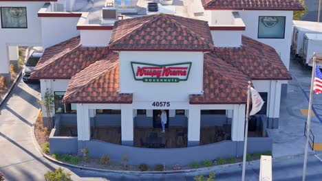 Temecula-Krispy-Kreme-Drone-Reverse-Pull-Back-Featuring-a-Person-Entering-and-Car-in-the-Drive-Thru-Lane-Pedestrian-on-Sidewalk